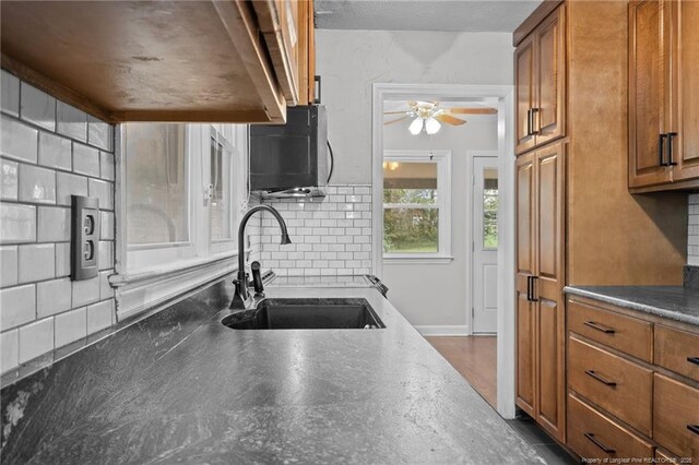 1905 Mcgougan Rd, Fayetteville, NC 28303 - kitchen with brown cabinetry, a ceiling fan, decorative backsplash, and black microwave