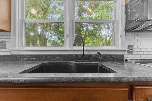 1905 Mcgougan Rd, Fayetteville, NC 28303 - kitchen with backsplash, dark countertops, brown cabinetry, and stainless steel microwave