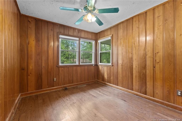 1905 Mcgougan Rd, Fayetteville, NC 28303 - spare room with hardwood / wood-style flooring, a textured ceiling, wood walls, and a ceiling fan