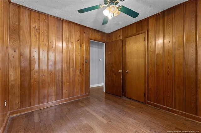 1905 Mcgougan Rd, Fayetteville, NC 28303 - empty room featuring wood finished floors, a textured ceiling, wooden walls, and ceiling fan