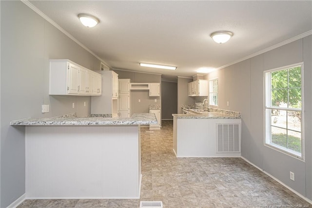 2990 Aberdeen Rd, Raeford, NC 28376 - kitchen with crown molding, a peninsula, light stone countertops, and white cabinets