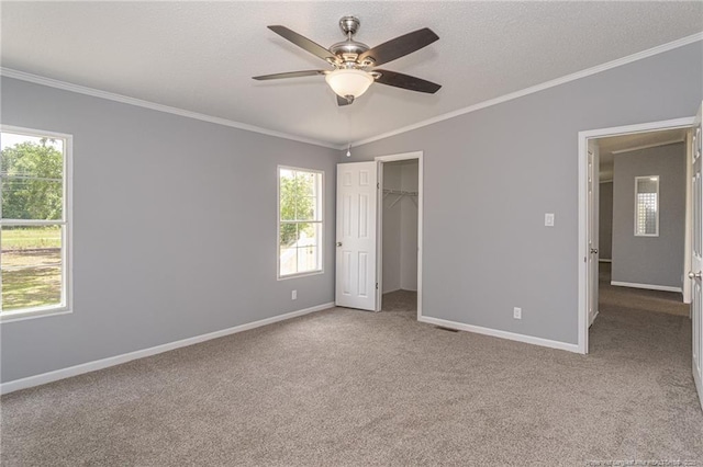 2990 Aberdeen Rd, Raeford, NC 28376 - unfurnished bedroom featuring ornamental molding, multiple windows, carpet flooring, ceiling fan, and a spacious closet