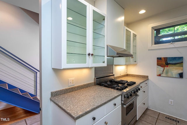 820 Runnymede Rd, Raleigh, NC 27607 - kitchen with high end stainless steel range oven, wall chimney range hood, white cabinets, light tile patterned floors, and recessed lighting
