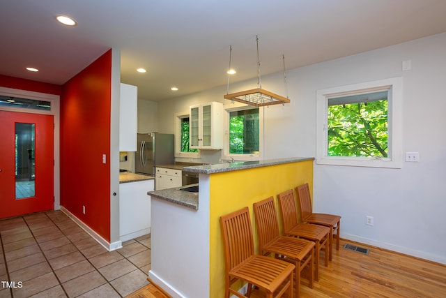 820 Runnymede Rd, Raleigh, NC 27607 - kitchen featuring freestanding refrigerator, white cabinetry, glass insert cabinets, recessed lighting, and a peninsula