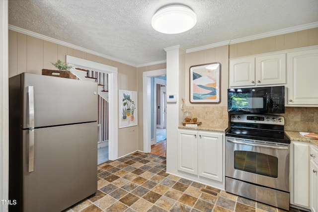 210 Peachtree St, Roxboro, NC 27573 - kitchen featuring stainless steel appliances, stone finish flooring, backsplash, white cabinetry, and ornamental molding