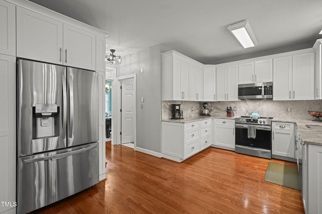 2925 Dargan Hills Dr, Wake Forest, NC 27587 - kitchen with appliances with stainless steel finishes, light wood-style floors, decorative backsplash, and white cabinets