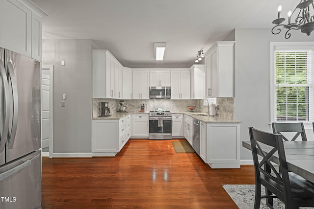 2925 Dargan Hills Dr, Wake Forest, NC 27587 - kitchen featuring appliances with stainless steel finishes, a chandelier, light stone countertops, tasteful backsplash, and dark wood finished floors
