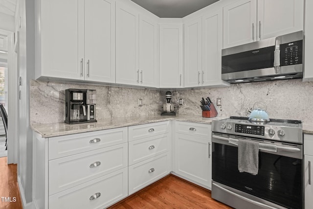 2925 Dargan Hills Dr, Wake Forest, NC 27587 - kitchen featuring appliances with stainless steel finishes, white cabinetry, light wood finished floors, light stone countertops, and decorative backsplash