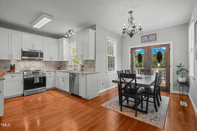 2925 Dargan Hills Dr, Wake Forest, NC 27587 - kitchen featuring appliances with stainless steel finishes, a chandelier, french doors, light wood finished floors, and white cabinetry
