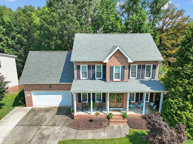 2925 Dargan Hills Dr, Wake Forest, NC 27587 - colonial-style house with covered porch, concrete driveway, a shingled roof, brick siding, and a garage