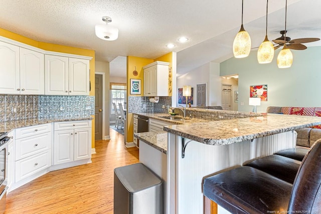 2 Beryl Cir, Pinehurst, NC 28374 - kitchen with a kitchen breakfast bar, light wood-type flooring, a peninsula, backsplash, and white cabinets