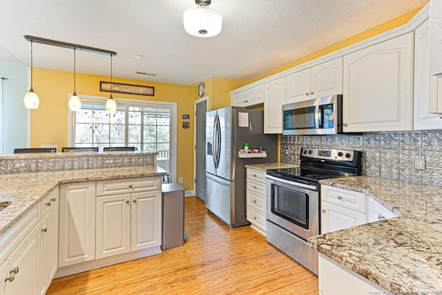 2 Beryl Cir, Pinehurst, NC 28374 - kitchen featuring appliances with stainless steel finishes, light wood finished floors, white cabinets, and tasteful backsplash