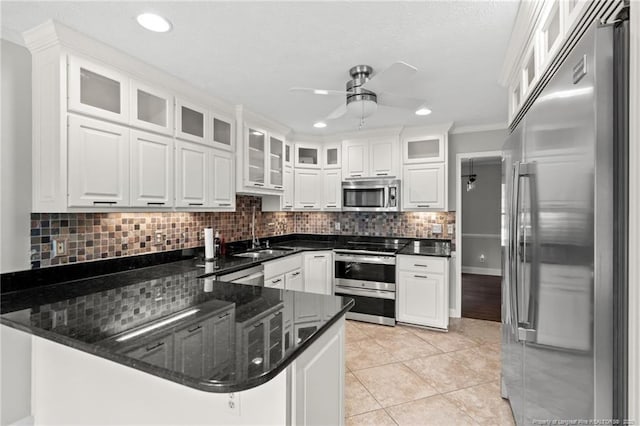 4304 Ferncreek Dr, Fayetteville, NC 28314 - kitchen with appliances with stainless steel finishes, a peninsula, ceiling fan, white cabinetry, and backsplash