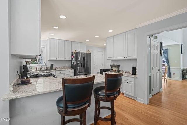 2401 Worthing Ct, Wake Forest, NC 27587 - kitchen with stainless steel refrigerator with ice dispenser, a peninsula, light stone counters, a kitchen breakfast bar, and recessed lighting