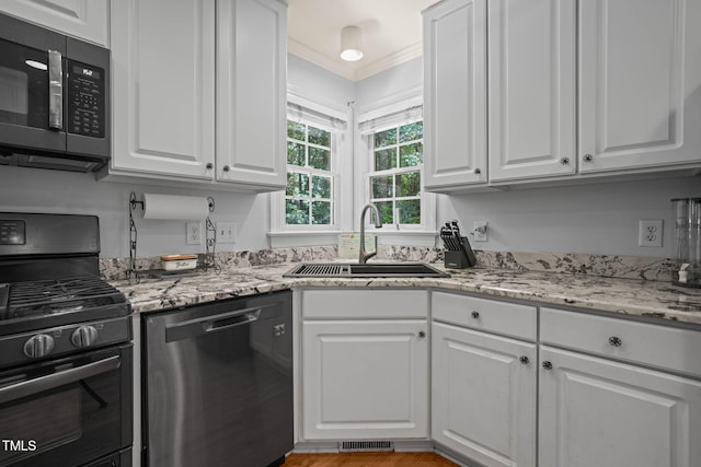 2401 Worthing Ct, Wake Forest, NC 27587 - kitchen with black appliances, white cabinets, light stone countertops, and ornamental molding