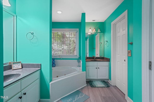 2401 Worthing Ct, Wake Forest, NC 27587 - full bathroom with two vanities, a jetted tub, and wood finished floors