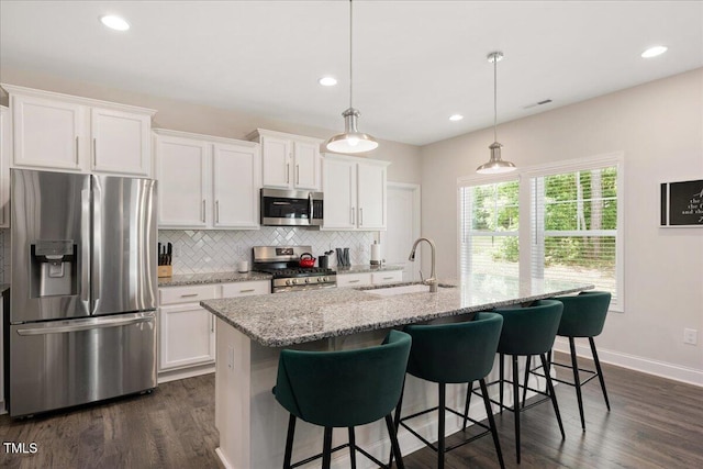 103 Foothill Ct, Sanford, NC 27330 - kitchen featuring appliances with stainless steel finishes, decorative backsplash, white cabinetry, a kitchen island with sink, and dark wood-style flooring