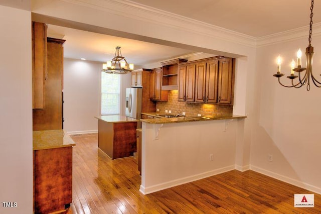 332 Bridgegate Dr, Cary, NC 27519 - kitchen with a chandelier, white refrigerator with ice dispenser, brown cabinetry, hardwood / wood-style flooring, and backsplash
