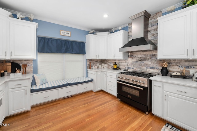 169 Skippers Lndg, Manson, NC 27553 - kitchen featuring wall chimney range hood, high end range, tasteful backsplash, white cabinetry, and light wood-type flooring