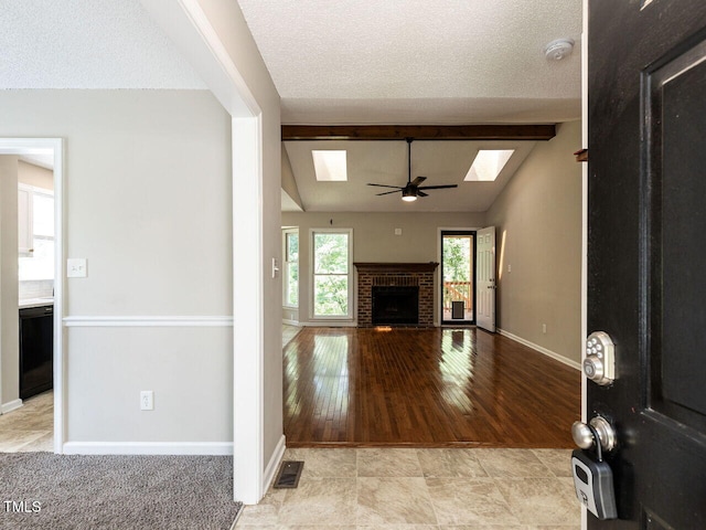 23 Joci Ct, Durham, NC 27704 - unfurnished living room with a skylight, a fireplace, ceiling fan, a textured ceiling, and light wood-style floors