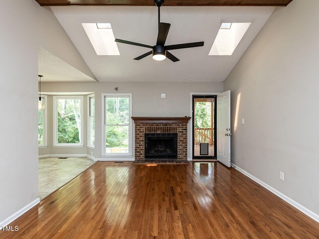 23 Joci Ct, Durham, NC 27704 - unfurnished living room featuring a skylight, wood-type flooring, a brick fireplace, a ceiling fan, and high vaulted ceiling