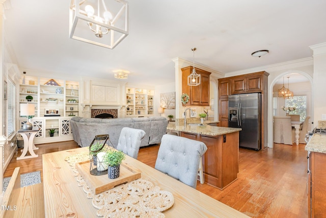 114 Boone Trl, Garner, NC 27529 - dining room with a chandelier, a brick fireplace, arched walkways, crown molding, and light wood finished floors