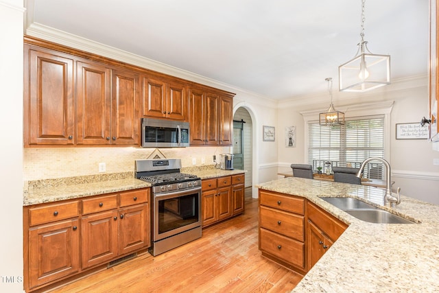 114 Boone Trl, Garner, NC 27529 - kitchen with appliances with stainless steel finishes, light wood-type flooring, pendant lighting, arched walkways, and crown molding