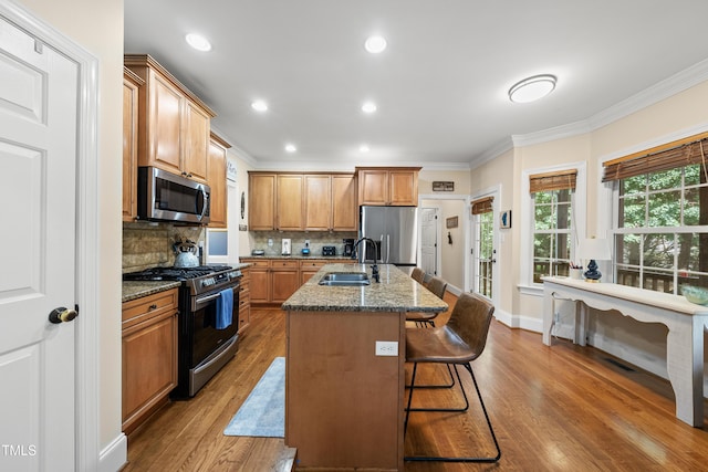 2027 River Grove Ln, Knightdale, NC 27545 - kitchen featuring appliances with stainless steel finishes, crown molding, wood finished floors, decorative backsplash, and a kitchen bar