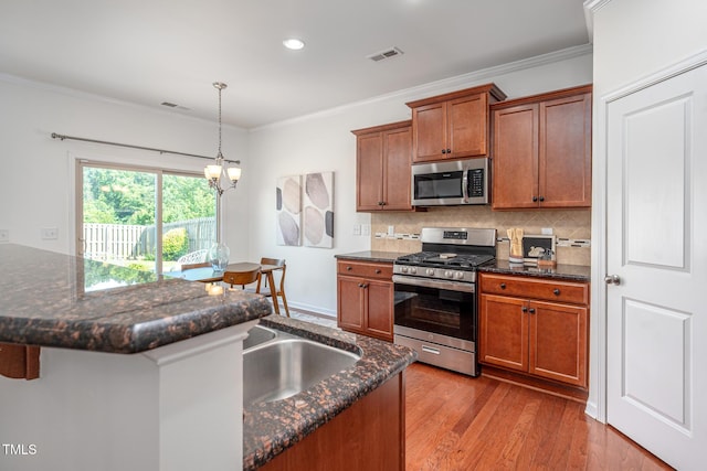 2007 October Dr, Durham, NC 27703 - kitchen with stainless steel appliances, backsplash, brown cabinets, wood finished floors, and ornamental molding