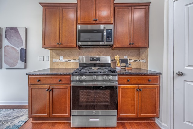 2007 October Dr, Durham, NC 27703 - kitchen with appliances with stainless steel finishes, wood finished floors, dark stone countertops, and backsplash