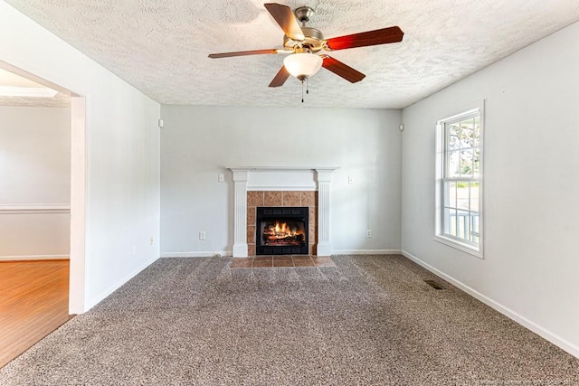 5228 Wallbrook Dr, Fayetteville, NC 28306 - unfurnished living room featuring a textured ceiling, a tiled fireplace, a ceiling fan, and carpet