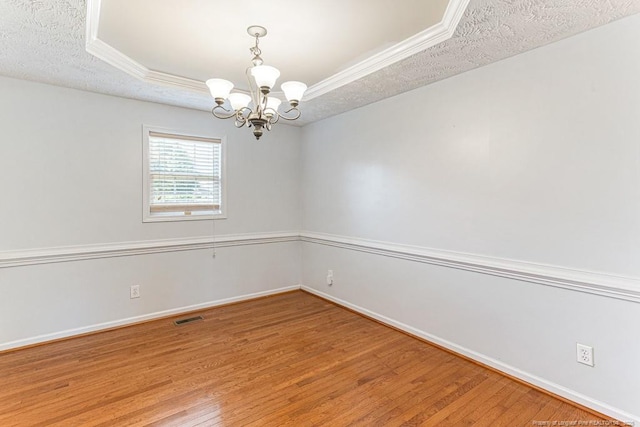 5228 Wallbrook Dr, Fayetteville, NC 28306 - unfurnished room with a chandelier, light wood-type flooring, a raised ceiling, crown molding, and a textured ceiling