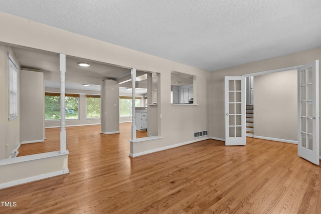 4404 Susan Dr, Raleigh, NC 27603 - unfurnished living room with french doors, light wood-style flooring, and a textured ceiling
