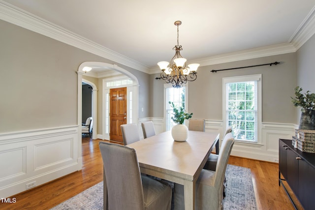 307 Beacon Falls Ct, Cary, NC 27519 - dining area featuring a chandelier, arched walkways, ornamental molding, light wood-style floors, and a wainscoted wall