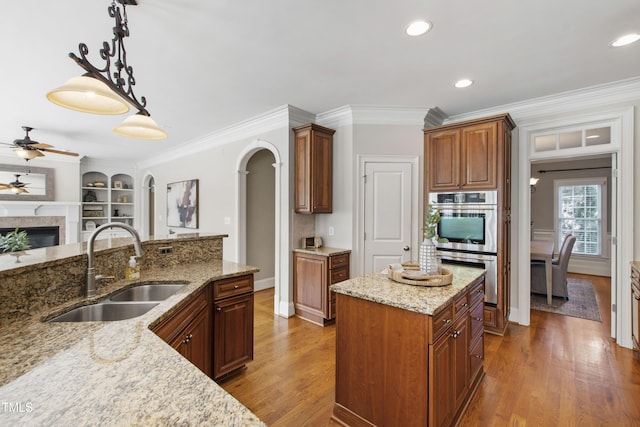 307 Beacon Falls Ct, Cary, NC 27519 - kitchen featuring stainless steel double oven, ceiling fan, wood finished floors, arched walkways, and light stone counters