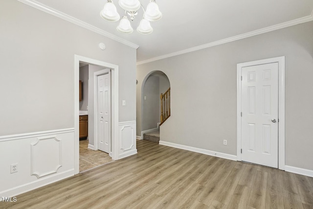 212 Cross Keys Ct, Cary, NC 27511 - spare room featuring arched walkways, ornamental molding, a chandelier, light wood-style flooring, and wainscoting