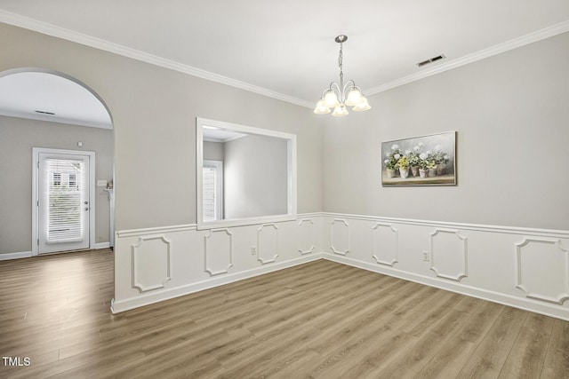212 Cross Keys Ct, Cary, NC 27511 - empty room with ornamental molding, wood finished floors, arched walkways, a chandelier, and wainscoting