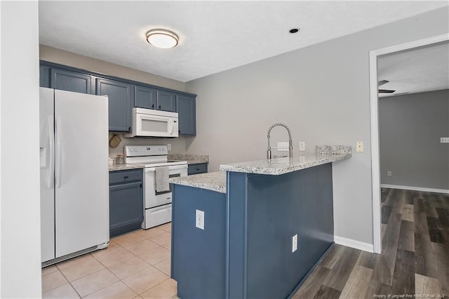 69 Ribbon Oak Ct, Sanford, NC 27332 - kitchen with white appliances, a peninsula, blue cabinets, and a kitchen breakfast bar