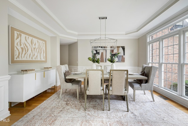500 Walcott Way, Cary, NC 27519 - dining room featuring a raised ceiling, a chandelier, healthy amount of natural light, wood finished floors, and a wainscoted wall