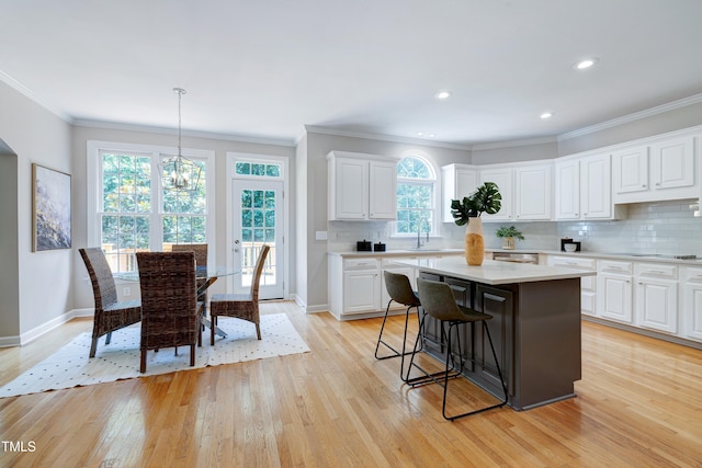 500 Walcott Way, Cary, NC 27519 - kitchen with light countertops, a breakfast bar, light wood-type flooring, a kitchen island, and ornamental molding