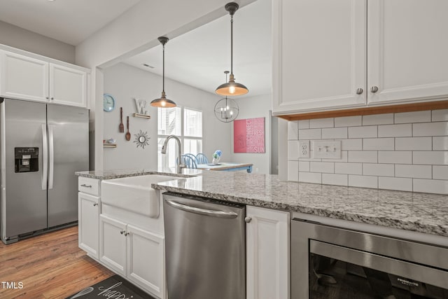 1006 Whistler St, Durham, NC 27713 - kitchen with appliances with stainless steel finishes, beverage cooler, white cabinetry, light wood-style floors, and tasteful backsplash