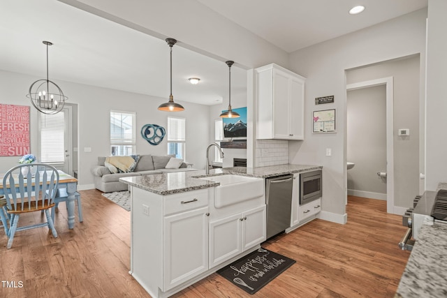 1006 Whistler St, Durham, NC 27713 - kitchen featuring appliances with stainless steel finishes, a peninsula, light wood-type flooring, white cabinets, and light stone countertops
