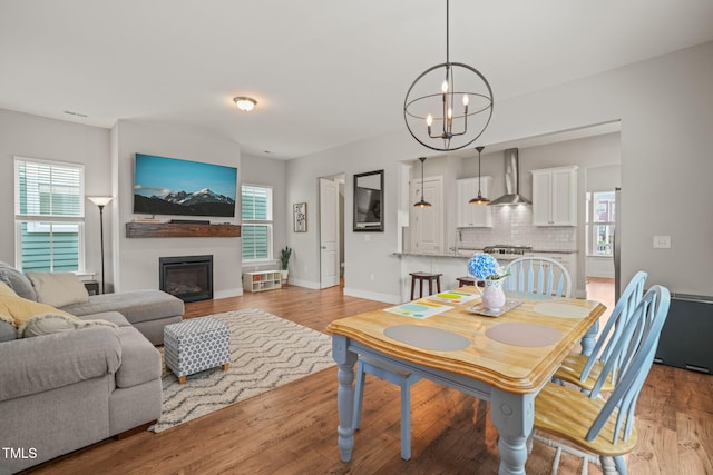 1006 Whistler St, Durham, NC 27713 - dining space featuring a chandelier, light wood-type flooring, and a glass covered fireplace