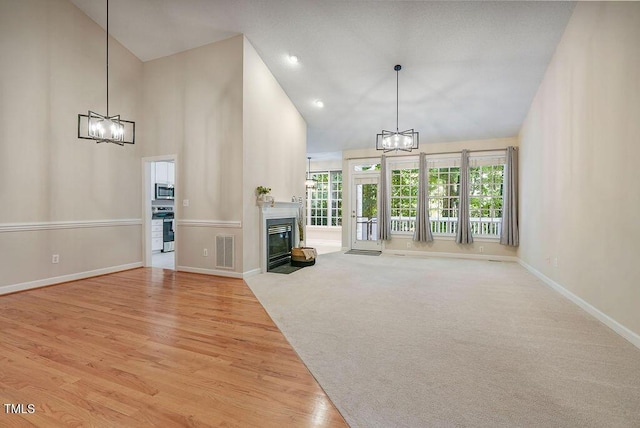 125 Chimney Rise Dr, Cary, NC 27511 - unfurnished living room featuring a chandelier, a fireplace with flush hearth, light wood-type flooring, high vaulted ceiling, and recessed lighting