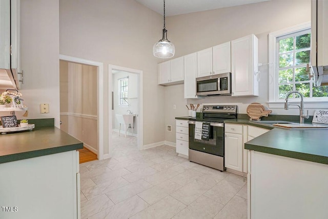125 Chimney Rise Dr, Cary, NC 27511 - kitchen featuring appliances with stainless steel finishes, dark countertops, white cabinets, high vaulted ceiling, and decorative light fixtures