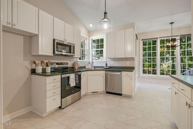 125 Chimney Rise Dr, Cary, NC 27511 - kitchen with stainless steel appliances, dark countertops, healthy amount of natural light, vaulted ceiling, and decorative light fixtures