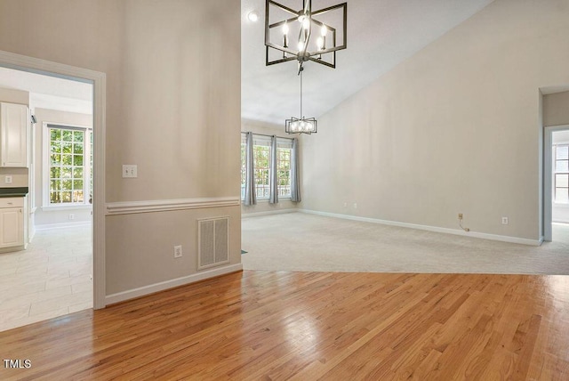 125 Chimney Rise Dr, Cary, NC 27511 - spare room featuring a chandelier, high vaulted ceiling, healthy amount of natural light, and light wood finished floors