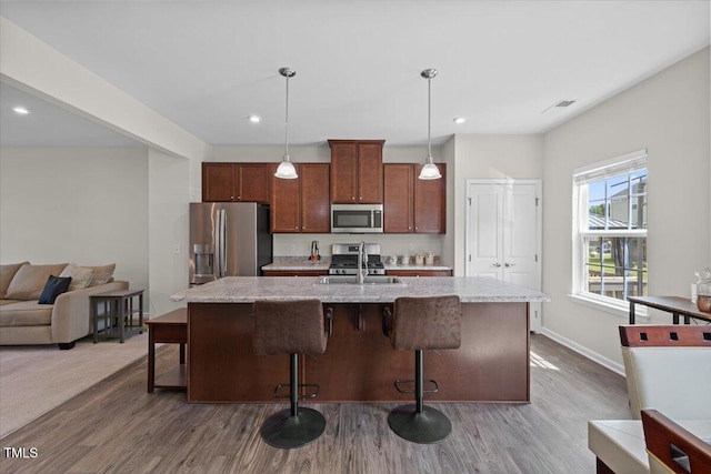 333 Amber Acorn Ave, Raleigh, NC 27603 - kitchen with appliances with stainless steel finishes, wood finished floors, a center island with sink, a breakfast bar, and recessed lighting