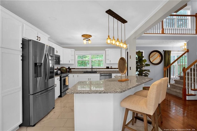 4010 Arcadia Ct, Fayetteville, NC 28311 - kitchen featuring appliances with stainless steel finishes, white cabinetry, a kitchen bar, ornamental molding, and light stone counters