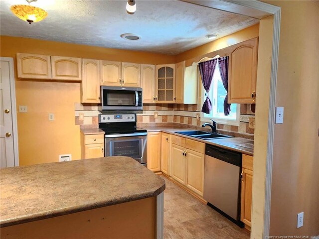 1519 Palmer Dr, Fayetteville, NC 28303 - kitchen with stainless steel appliances, backsplash, light brown cabinetry, and glass insert cabinets